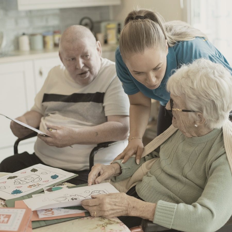 A caregiver helping older adults with a craft activity