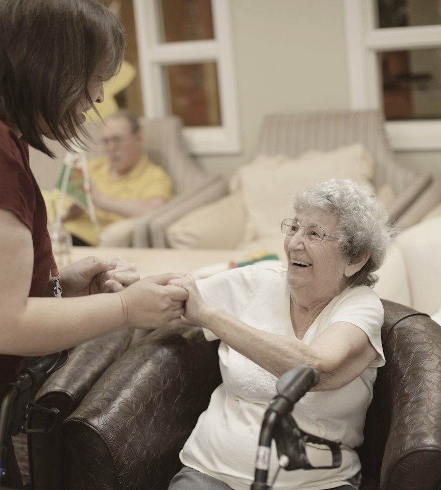 A caregiver holding hands with a smiling older woman